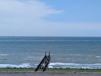 Das Bild zeigt eine Buhne, die ins Meer verl&auml;uft, vom Strand aus fotografiert.